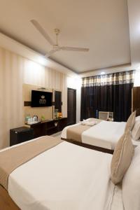 um quarto de hotel com duas camas e uma televisão em Hotel Krone By RMAAP Hotels em Nova Deli