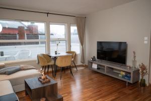 Una sala de estar con un sofá, un televisor y una mesa. en Cozy Penthouse Private Balcony City Centre, en Stavanger