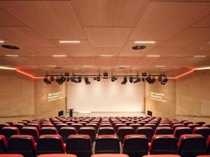 an empty lecture hall with a white screen and red chairs at Hotel Ski Austria St.Christoph a.A. in Sankt Christoph am Arlberg