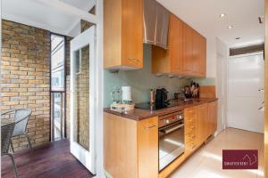 a kitchen with wooden cabinets and a brick wall at Richmond Three Bedroom Flat in Whitton