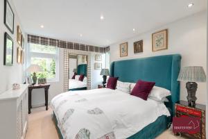 a bedroom with a large bed with a blue headboard at Richmond Three Bedroom Flat in Whitton