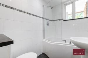 a white bathroom with a tub and a sink at Richmond Three Bedroom Flat in Whitton