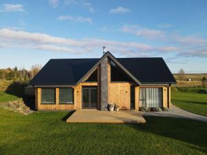 een huis met een zwart dak op een groen veld bij Garden Villa ' Lava Forest ' in Selfoss
