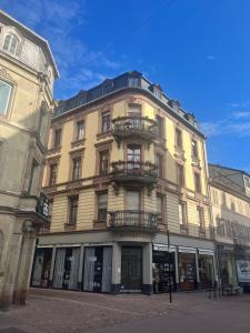 a tall yellow building with a balcony on a street at Appartement de style 70 in Colmar