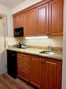 une cuisine avec des armoires en bois et un évier dans l'établissement Waterloo Suites Hotel, Trademark Collection by Wyndham, à Waterloo