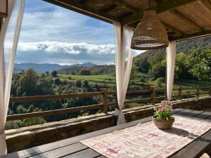 a porch with a table and a view of the mountains at Masia d'Els Plans in Vidrá