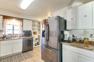 Una cocina con gabinetes blancos y un refrigerador de acero inoxidable. en Easy OKC Access! Quiet Home with Yard and Workspace, en Midwest City