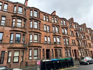 a large brick building with cars parked in front of it at A delightful and cozy one bedroom flat in Glasgow