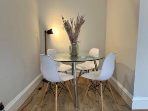 a dining room with a glass table and white chairs at A delightful and cozy one bedroom flat in Glasgow +8 photos