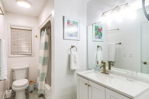 a white bathroom with a sink and a toilet at 4 Mi to St Simons Beach Modern Getaway with Sunroom in Blackbanks +21 photos