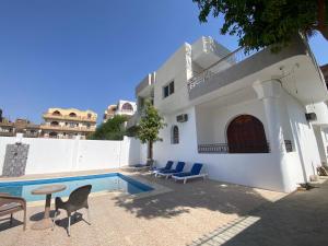 a house with a swimming pool and chairs and a table at Villa Acamar in Al Karnak