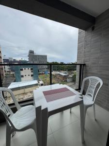 a table and two chairs on a balcony with a view at Dutra Ocean · Apartamento completo próximo à praia com academia in Mongaguá