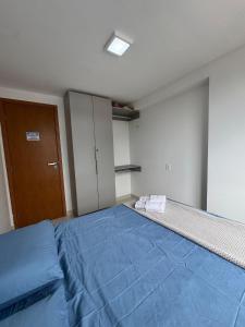 a bedroom with a bed with blue sheets and a door at Dutra Ocean · Apartamento completo próximo à praia com academia in Mongaguá