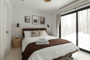 ein Schlafzimmer mit einem großen Bett mit zwei Handtüchern darauf in der Unterkunft Forest Refuge - Fire - HotTub - Tremblant 15 min in La Conception