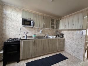 a kitchen with wooden cabinets and a sink and a stove at Conforto e espaço garantido no Bessa in Nossa Senhora do Livramento