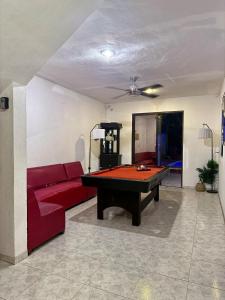 a living room with a red couch and a pool table at Alojamiento para 3 personas con alberca y billar in Chuburná de Hidalgo