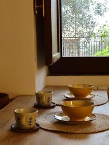Quatro tigelas e pires sobre uma mesa em frente a uma janela. em Dimidia - casa vacanze mare montagna em Capaci