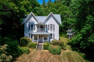 a white house with a porch and trees at Historic McGuire House in Todd