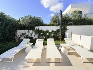 a row of white benches in a garden at 797 HOLIDAY RENTALS - Lujosa y moderna villa en Puerto marina in Benalmadena Costa