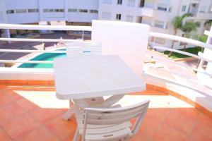 a white table and a chair on a balcony at BOUZNIKA Piscine et plage in Bouznika