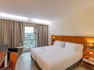 Una habitación de hotel con una cama grande y un escritorio. en Hotel Mercure Lisboa, en Lisboa 74 fotos más