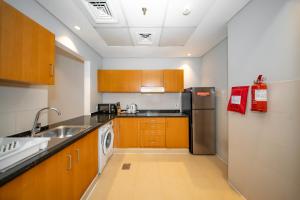 ドバイにあるCity Stay Grand Hotel Apartments - Al Barshaのシンクと冷蔵庫付きのキッチン
