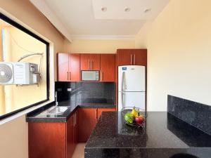 una cocina con armarios de madera y un bol de fruta en la barra en Suite cómoda, en Machala