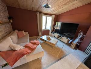 a living room with a couch and a flat screen tv at Gite Chez Tof et Ninie in Houlle