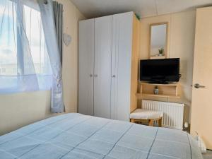 ein Schlafzimmer mit einem Bett, einem Fernseher und einem Fenster in der Unterkunft Ocean Breeze in Truro + 15 Fotos