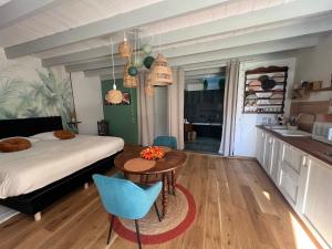 a bedroom with a bed and a table and a kitchen at Studio de charme à la campagne & SPA privatif pour deux in Saint-Maurice-de-Laurençanne