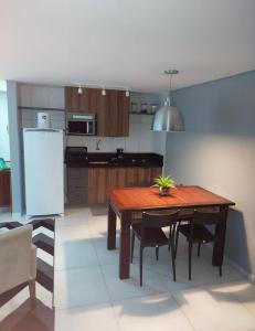 a kitchen with a wooden table with chairs and a refrigerator at Flat perto do MAR in Cabedelo +21 photos