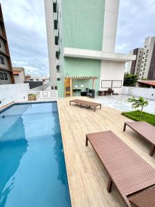 a pool on the roof of a building with benches at Flat perto do MAR in Cabedelo
