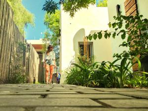 a woman walking down a street with a hat on at Botanico in Villa Elisa