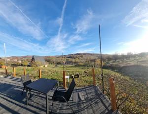 a table and chairs on a deck with a view of a field at GlampingDenis Igloo in Mihăeşti +5 photos