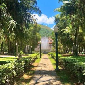 Un paseo a través de un parque con árboles y una fuente. en Lumiére, en Poços de Caldas
