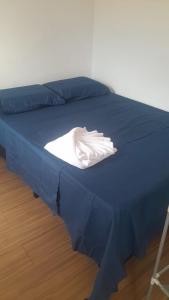 una cama azul con una camisa blanca encima en Casa completa, 2 quartos, com ar condicionado, en Hortolândia