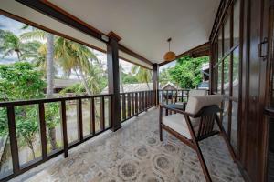 a balcony with a desk and a chair on it at Maison Lake View Luang Prabang in Luang Prabang
