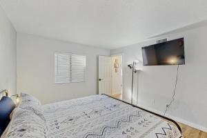 a white bedroom with a bed and a flat screen tv at Mtn-View Condo w/ Resort Amenities in Tucson! in Tucson