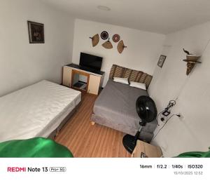 a small bedroom with two beds and a television at Nina House, Cali, Valle del Cauca in Cali