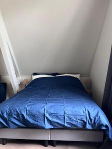 a bed with a blue comforter in a bedroom at Hoeve Herweijer in Strijensas