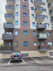 Un coche aparcado en un estacionamiento frente a un edificio. en Apartman Havjar Zlatibor, en Zlatibor