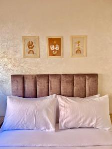 a bed with white pillows and three pictures on the wall at A12 Studio cosy Tamraght Idéal nomades & surfers in Tamraght Ouzdar