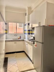 a kitchen with white cabinets and a refrigerator at A12 Studio cosy Tamraght Idéal nomades & surfers in Tamraght Ouzdar +37 photos