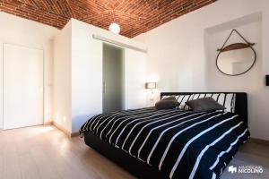 a bedroom with a bed with a black and white striped comforter at CASA JACK Open Space Piazza Galimberti in Cuneo