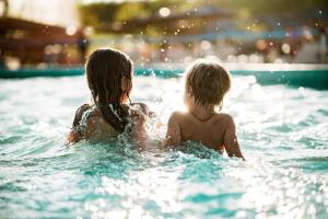 two children in the water in a swimming pool at Holiday Inn Express & Suites DFW Airport Southwest - Euless by IHG in Euless