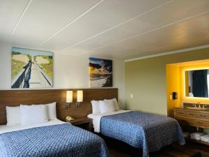 斩魔山Mariner Inn And Suites的有两张床和一面镜子的酒店房间