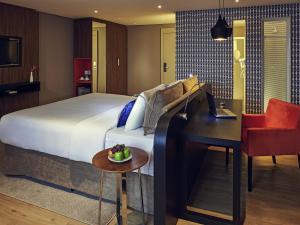 ブラジリアにあるGrand Mercure Brasilia Eixo Monumentalのベッドと机とテーブルがあるホテルの部屋