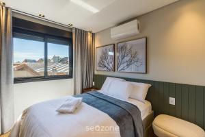 a bedroom with a bed and a large window at DLH - Apartamentos no Coração de Gramado Próximos à Rua Coberta in Gramado