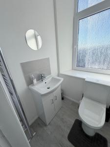 Un baño con lavabo, inodoro y ventana. en Apartment 3- 216 high Street, en Arbroath