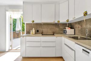a white kitchen with white cabinets and a sink at Luxury & Central Arendal Home in Arendal
